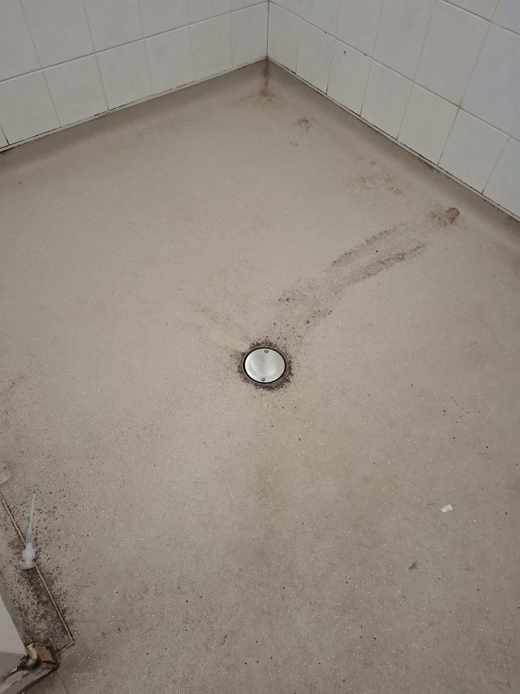 Grimy changing room washroom floor at Needham Market FC before Eastrada deep clean, dirt built up around the drain and edges